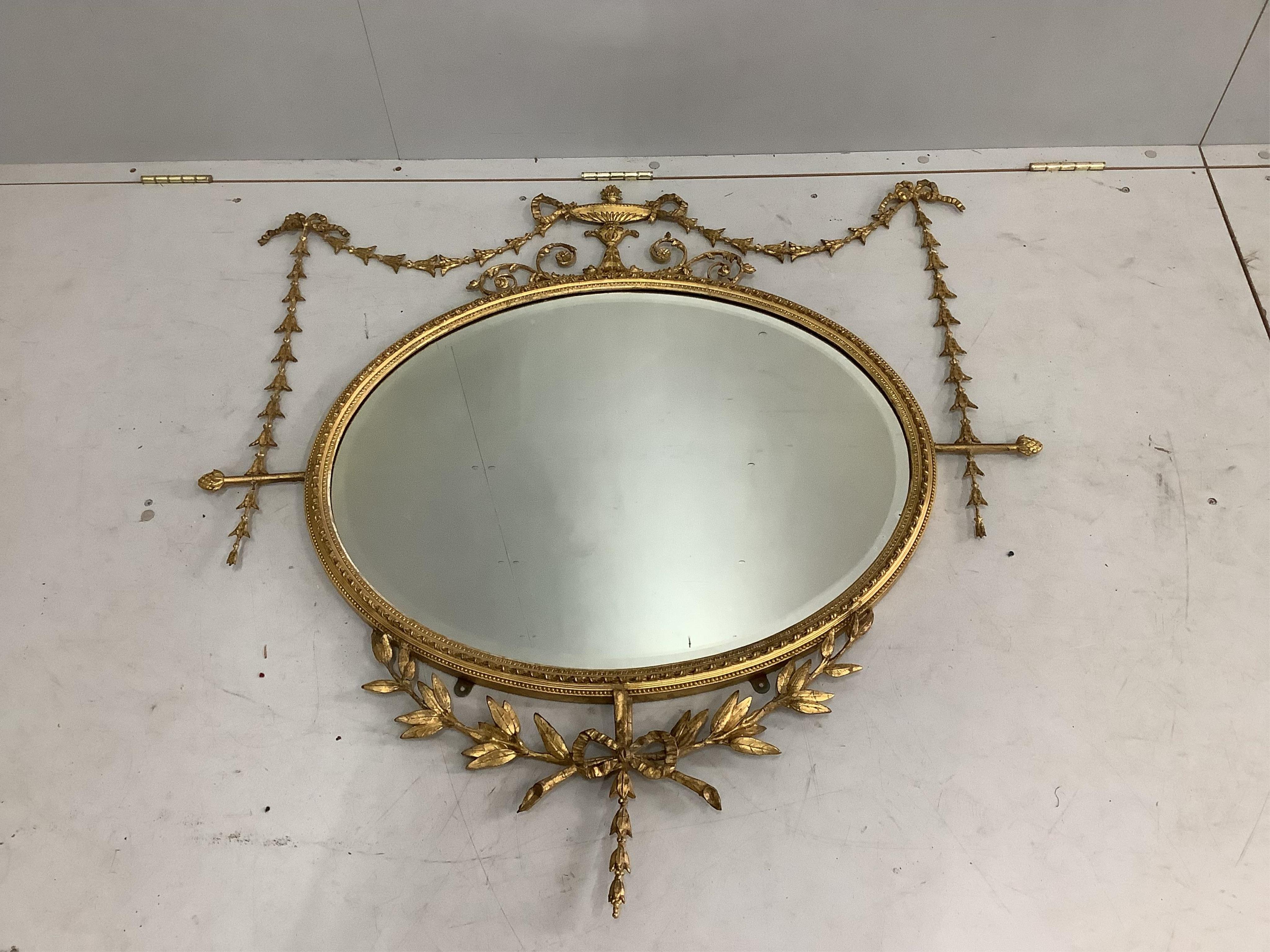 An Edwardian Sheraton style oval giltwood and composition wall mirror, width 105cm, height 106cm. Condition - good